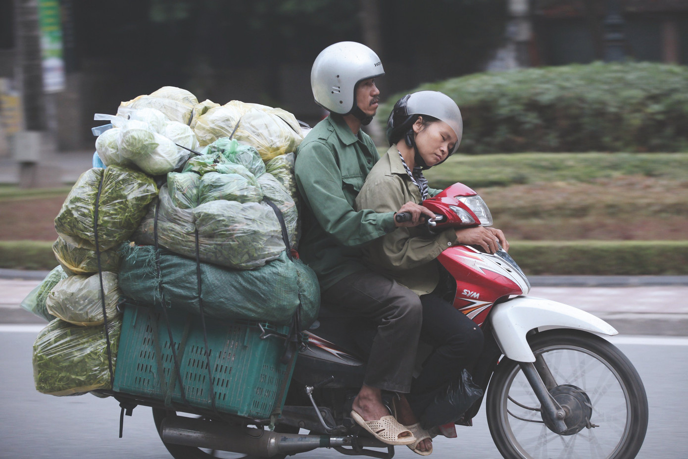 Hai vợ chồng một tiểu thương chở rau từ Hòa Bình vào Hà Nội, người vợ tranh thủ ngủ trên xe vì phải dậy sớm thu mua rau