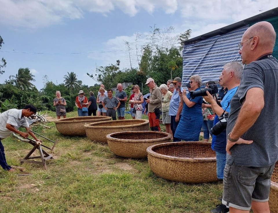 Du khách nước ngoài xem ông Trương Văn Trung làm thúng chai bằng phương pháp thủ công Ảnh: Công Hoan