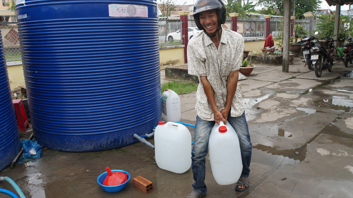 Ông Nguyễn Văn Thảo ở xã An Hóa (Châu Thành, Bến Tre) bê từng thùng nước ngọt. Ảnh: HÒA HỘI