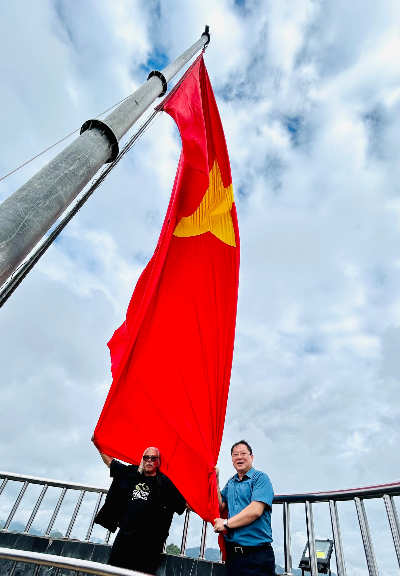 Tác giả và nhà báo Xuân Ba với lá cờ trên Cột cờ Lũng Cú. Ảnh: Sĩ Lực