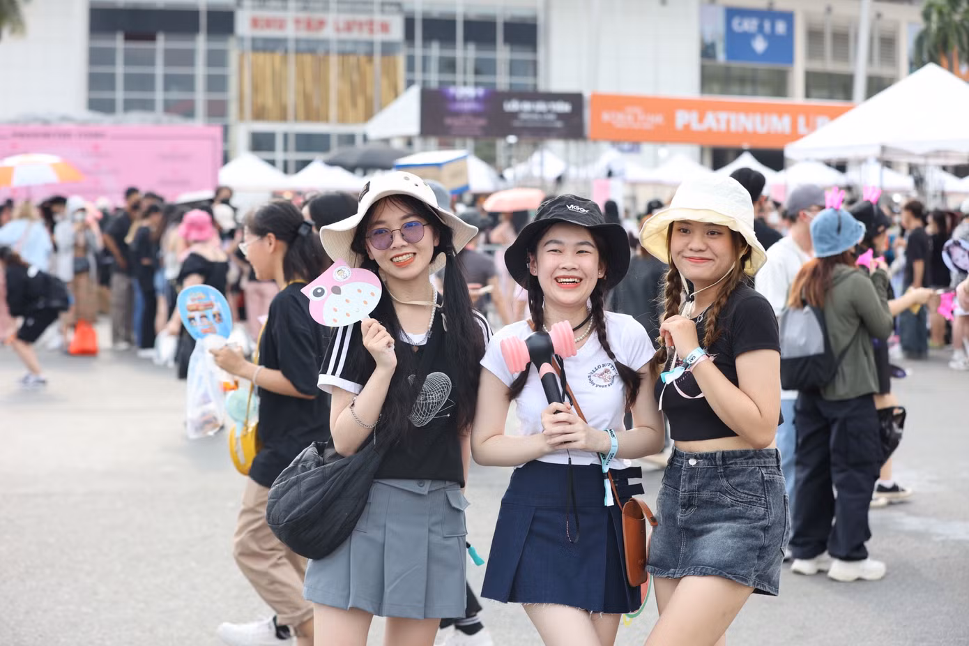 Fan nữ diện trang phục theo phong cách thần tượng, mang theo vật phẩm cổ vũ hào hứng chờ đến giờ diễn.