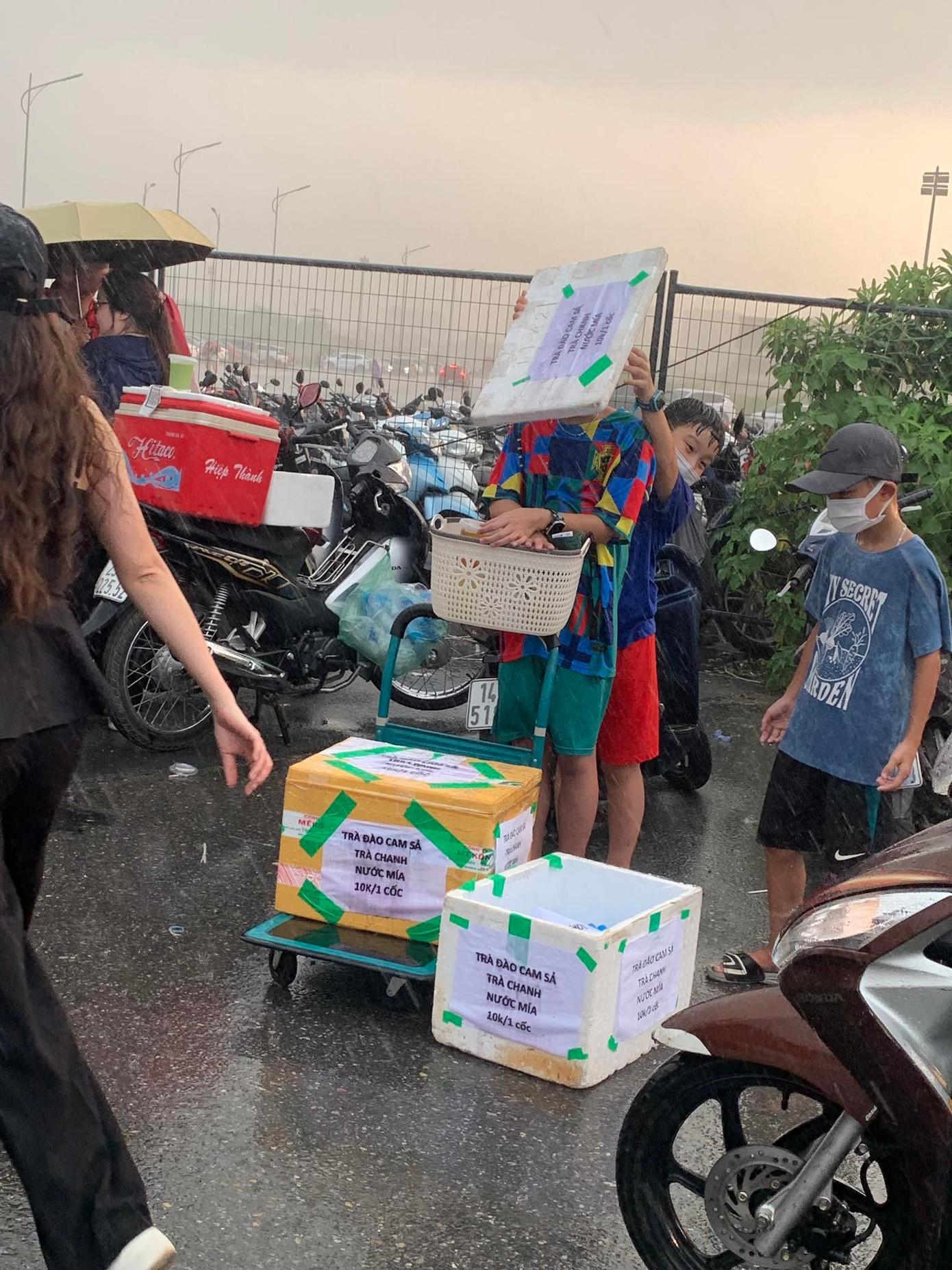 Các em nhỏ bán hàng chịu ướt che chắn cho những thùng đồ uống.