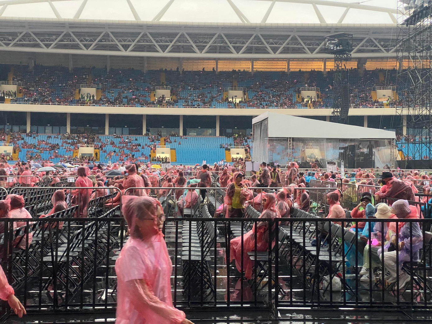 Bên trong khu vực sân khấu, nhiều người bắt đầu ổn định chỗ ngồi. Vì không có mái che, mọi người đều chịu cảnh ngồi dưới mưa. Bên trong khu vực sân khấu, nhiều người bắt đầu ổn định chỗ ngồi. Vì không có mái che, mọi người đều chịu cảnh ngồi dưới mưa.