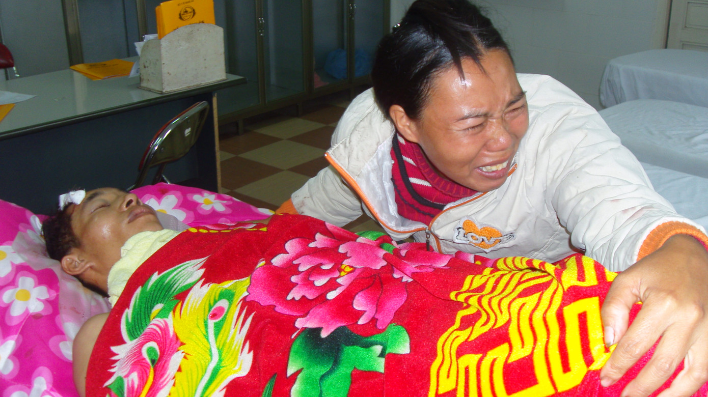 Chị Vy Thị Thích (vợ anh Cường) bật khóc bên chồng. Chị Thích cho biết, chồng chị đi bốc gỗ thuê đêm 06-12 chỉ đế kiếm cho con 100.000 đồng mua gạo.