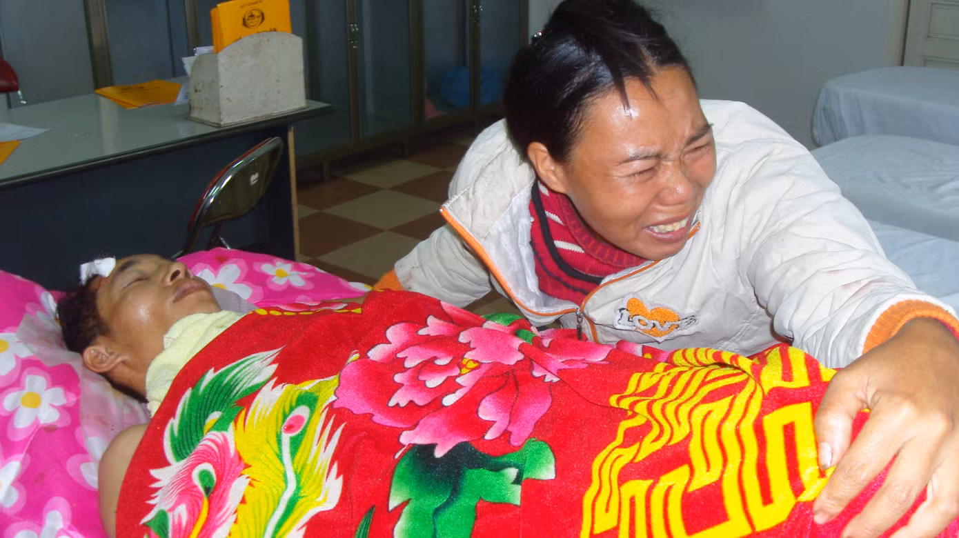 Chị Vy Thị Thích (vợ anh Cường) bật khóc bên chồng. Chị Thích cho biết, chồng chị đi bốc gỗ thuê đêm 06-12 chỉ đế kiếm cho con 100.000 đồng mua gạo.