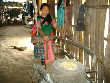 Vừa địu con vừa xay lúa