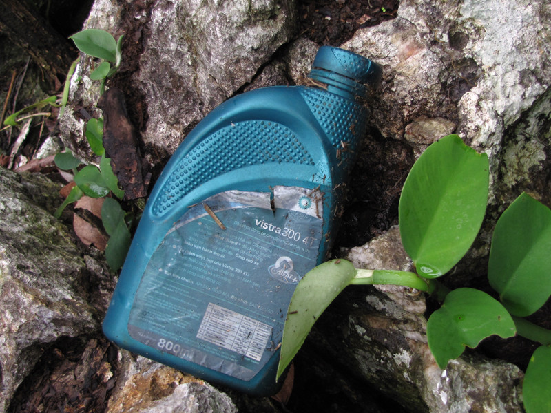 Một bình dầu nhớt chạy máy vứt bỏ trong khe đá