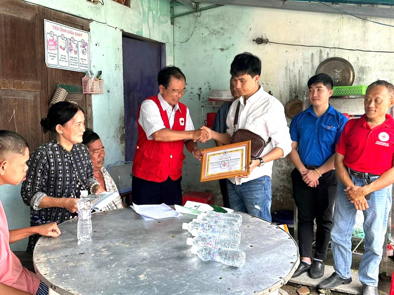 Anh Lê Thanh Trung (áo trắng) trao hỗ trợ cho bà Nguyễn Thị Hồng nuôi 3 con bệnh tật và được cơ quan chức năng địa phương tri ân.