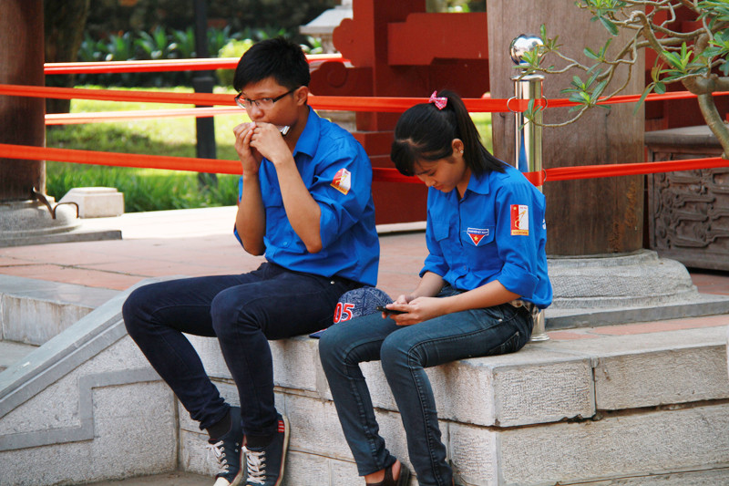 Nam sinh viên tình nguyện thổi kèn cho bạn nữ nghe trong khi làm nhiệm vụ trông coi Gác trống trong Văn Miếu. Ảnh: Trường Phong 