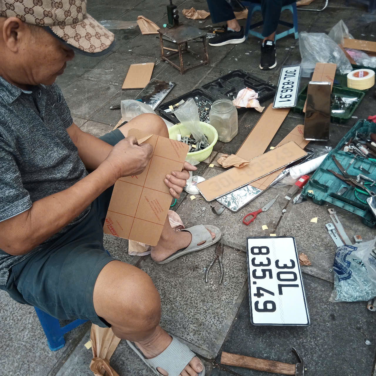 Cán bộ CSGT tất bật làm thủ tục (ảnh trái), bên cạnh đó là cảnh "nhộn nhịp" dịch vụ lắp biển. Cán bộ CSGT tất bật làm thủ tục (ảnh trái), bên cạnh đó là cảnh "nhộn nhịp" dịch vụ lắp biển.