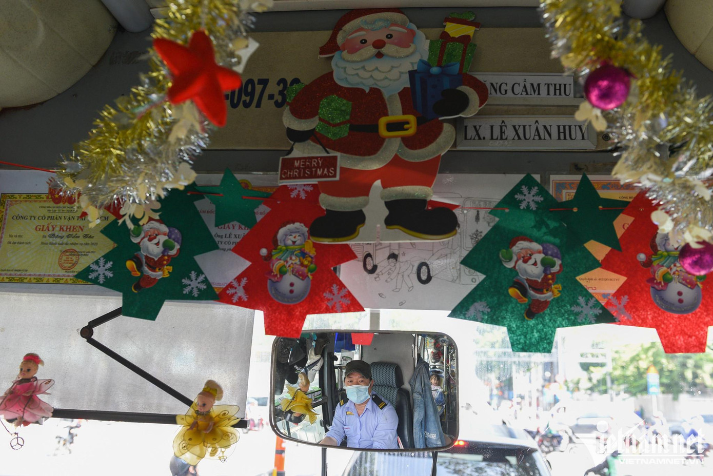 Đầu xe, tài xế treo bằng khen của hai vợ chồng cùng tranh vẽ xe bus, trang trí thêm bằng ruy băng lấp lánh, búp bê, hình dán nhiều màu in hình chủ đề Giáng sinh sinh động. Đầu xe, tài xế treo bằng khen của hai vợ chồng cùng tranh vẽ xe bus, trang trí thêm bằng ruy băng lấp lánh, búp bê, hình dán nhiều màu in hình chủ đề Giáng sinh sinh động.