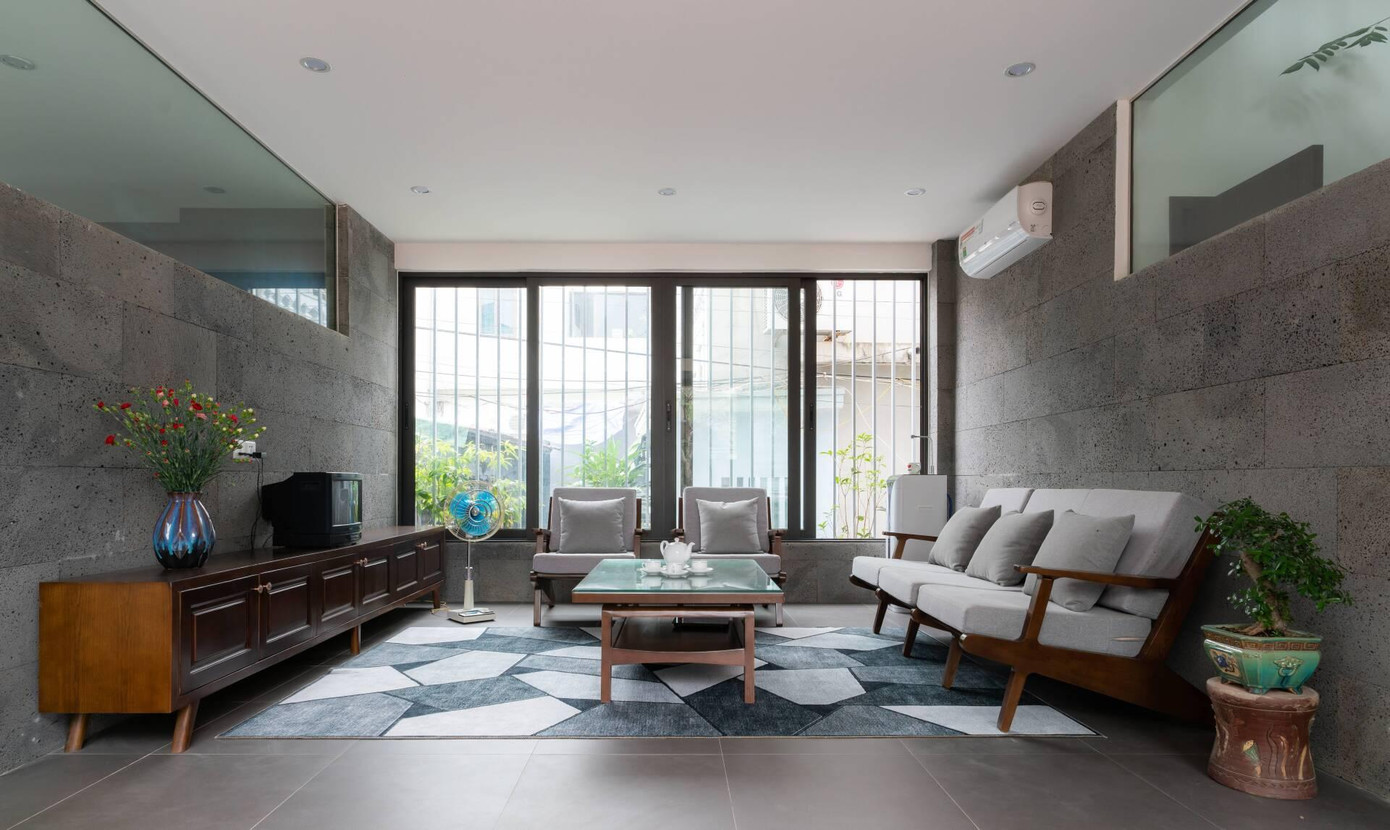 Nhờ tường kính, nhiều cửa sổ mà tất cả các không gian chính đều có ánh sáng tự nhiên và được tiết chế cường độ bởi hệ thống cây xanh đan xen. Mặt sau của nhà giáp với một con ngõ nhỏ nên KTS mở thêm cửa lớn phía sau và tạo hệ khung sắt để đảm bảo an ninh cho gia chủ vừa tạo giàn leo cho những cây hoa dần dần sẽ phủ kín thành một bức tường cây xanh.