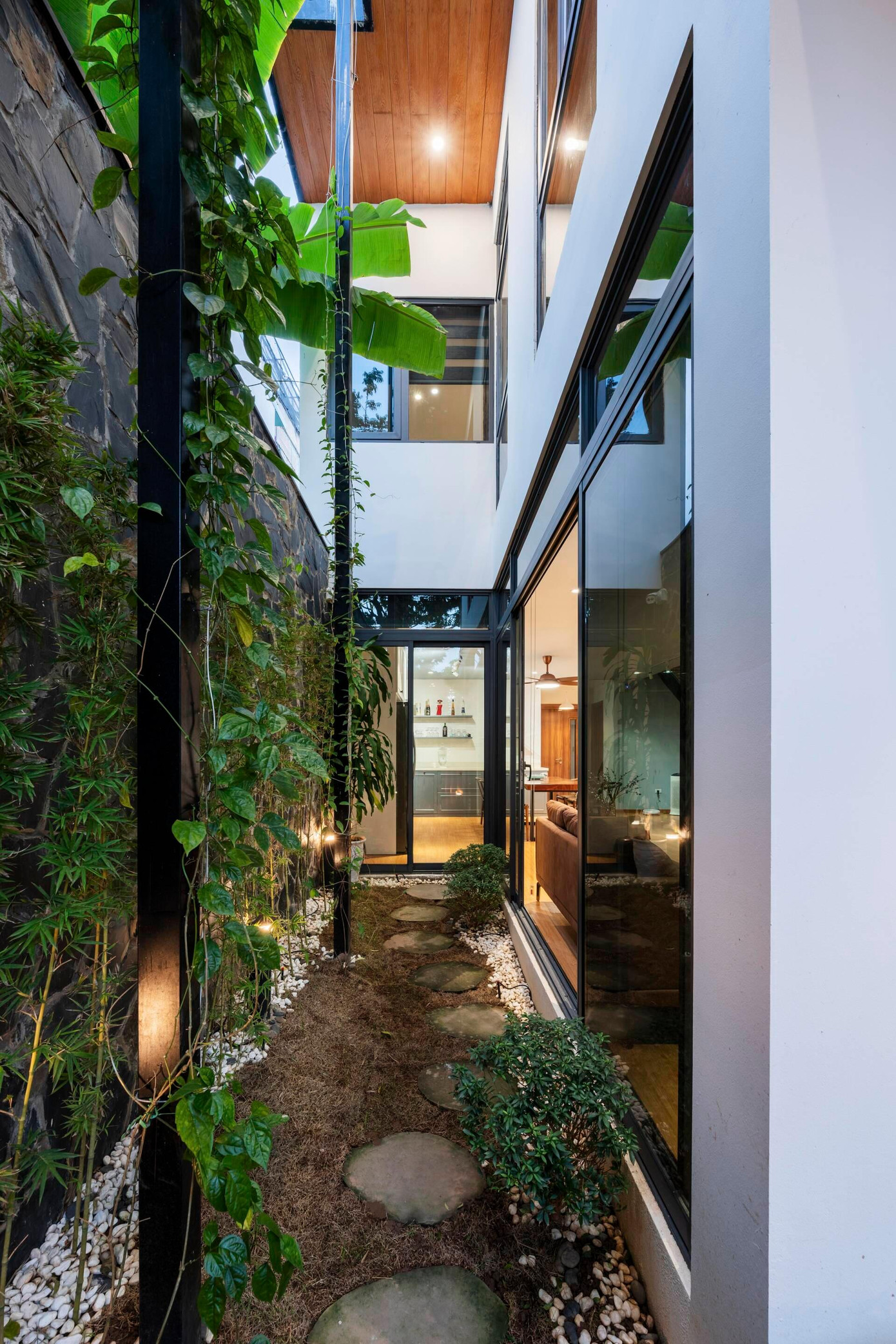 Sân vườn chạy dọc theo chiều dài của ngôi nhà trồng trúc cảnh và một số cây dây leo, khu vực này cũng có tác dụng thông gió cho ngôi nhà.