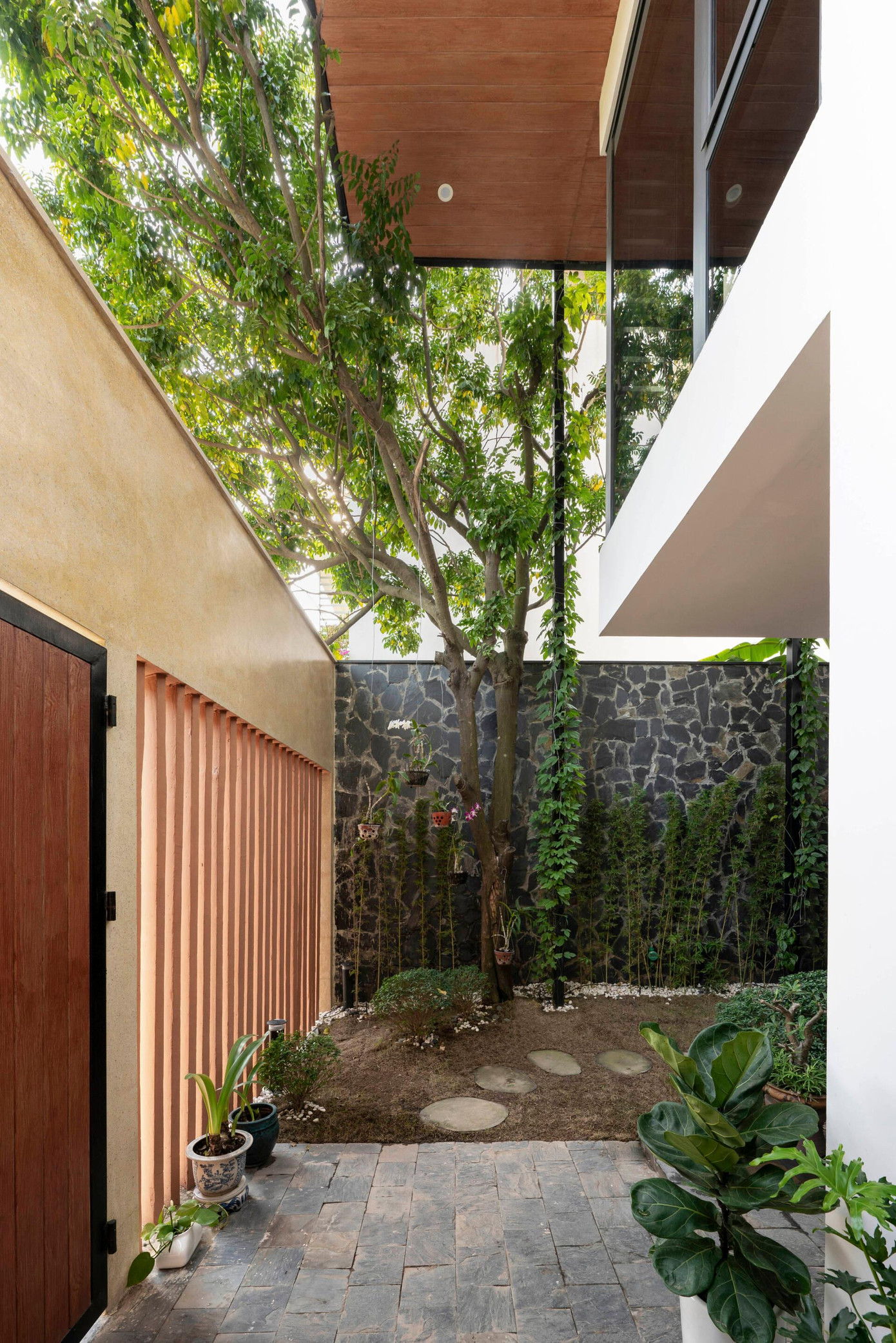 Theo đó, hai khoảng sân vườn vừa giải quyết được vấn đề đối lưu gió trước - sau cho ngôi nhà, vừa có thể giữ lại cây xanh được gia đình trồng hơn 1 thập kỷ.