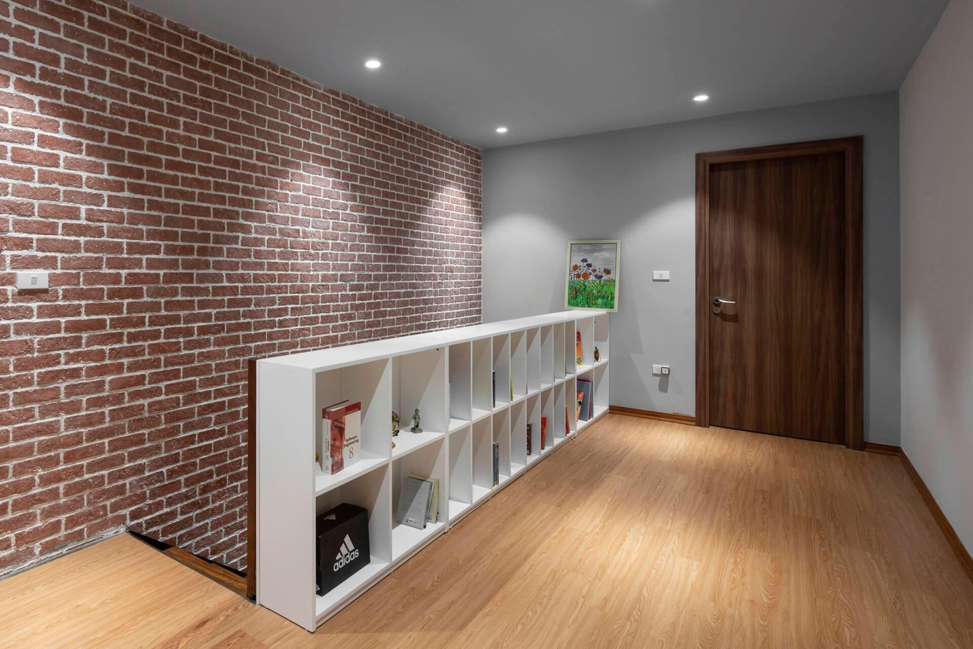 Ở tầng 1 còn có phòng ngủ cho người lớn tuổi. Cầu thang dẫn lên tầng 2 được đẩy sát vào 1 bên tường để tăng diện tích và công năng sử dụng. Hành lang cầu thang tầng 2 còn được tận dụng làm kệ để sách của gia đình.