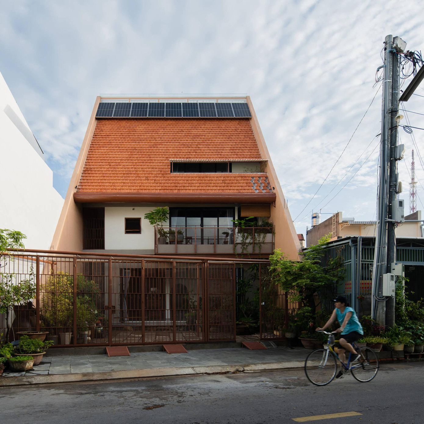 Do đó KTS quyết định lấy mái ngói đỏ làm điểm nhấn của công trình trong khi hai mảng tường hai bên sơn màu cam đất để tôn lên vẻ đẹp của hệ mái. Để tiết kiệm điện năng cho ngôi nhà, KTS lắp hệ thống pin năng lượng mặt trời trên mái.