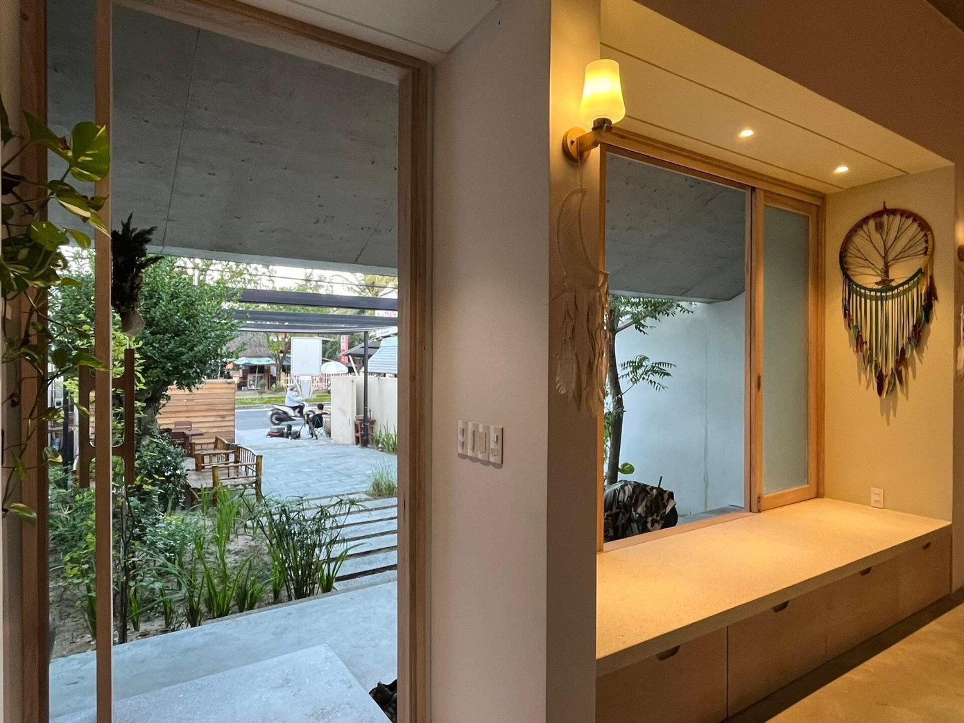 Từ khu vườn trước bước lên nhà sẽ bắt gặp khoảng hiên rộng với bậc tam cấp đá. Hiên nhà còn đóng vai trò như phòng khách nên gia chủ đặt ghế đóng từ gỗ của nhà cũ, bên cạnh là bệ cửa sổ để tiếp khách hay làm nơi đọc sách hoặc uống trà.