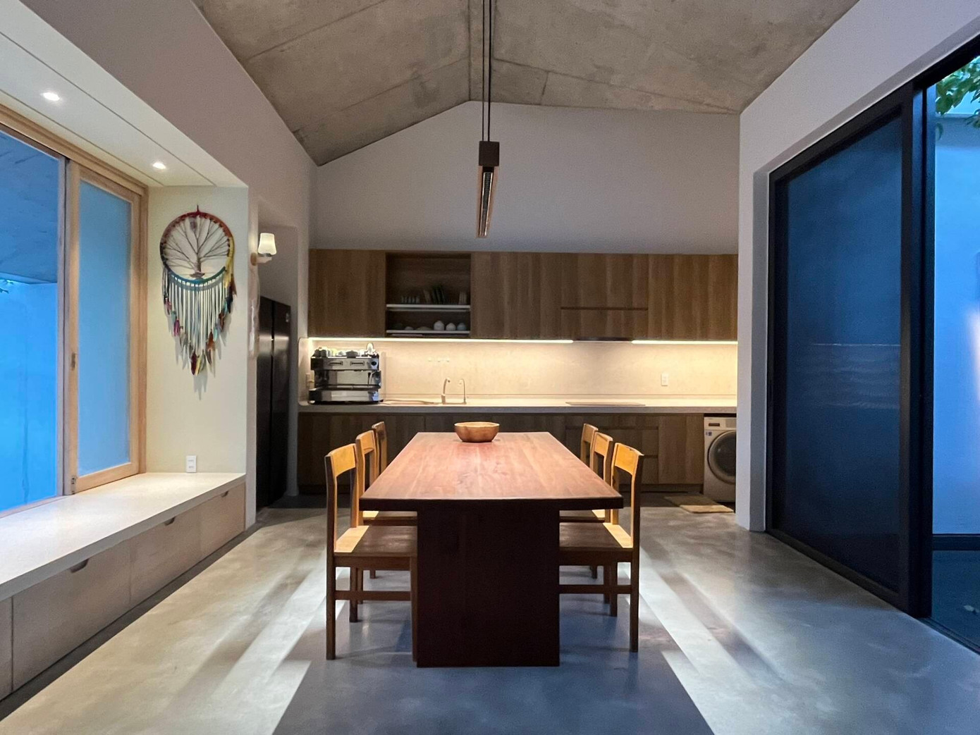 Từ hiên bước vào sẽ bắt gặp khu vực bếp và phòng ăn rộng rãi. Tủ bếp và bàn ăn được làm bằng gỗ công nghiệp, còn mặt bếp là đá mài.