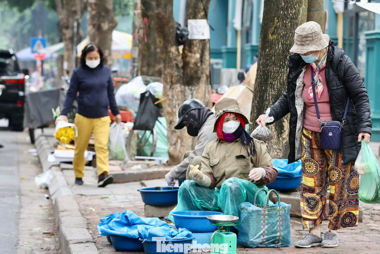Trời mưa rét khiến công việc kinh doanh gặp khá nhiều khó khăn, lượng mua chậm, nhiều người ngả cả ô to để che chắn gió lùa ngồi ngóng khách.