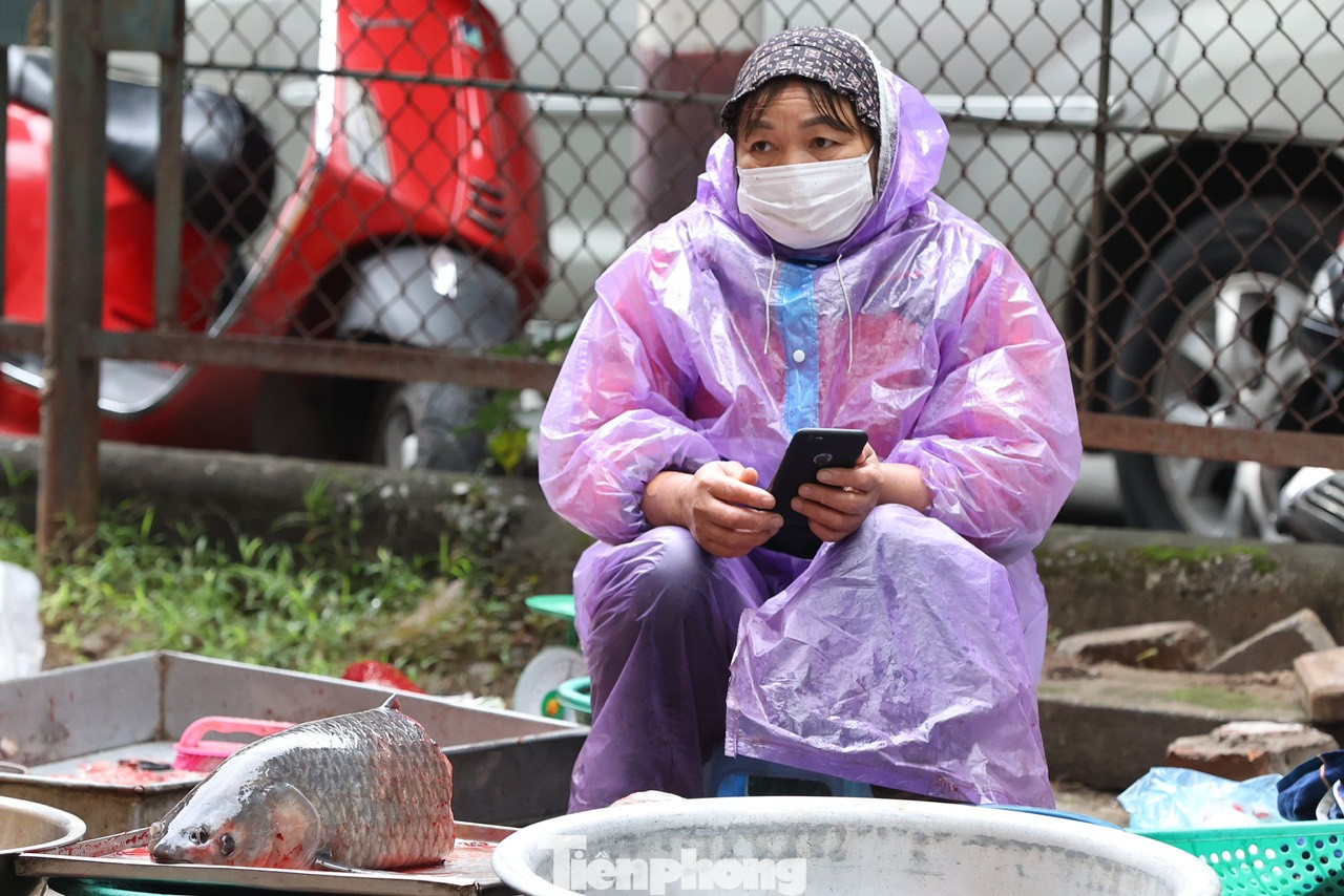 Trời mưa rét khiến công việc kinh doanh gặp khá nhiều khó khăn, lượng mua chậm, nhiều người ngả cả ô to để che chắn gió lùa ngồi ngóng khách.