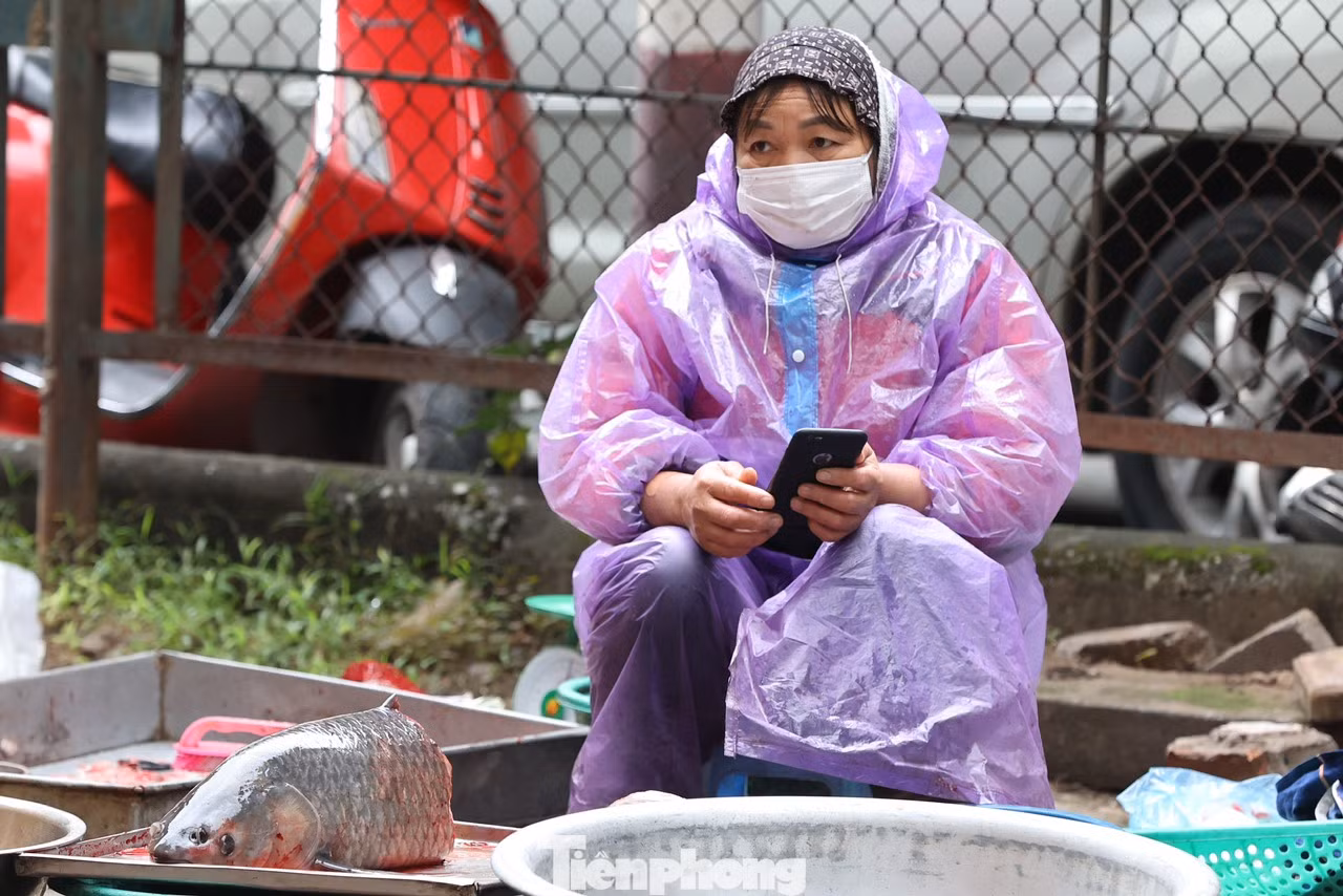 Trời mưa rét khiến công việc kinh doanh gặp khá nhiều khó khăn, lượng mua chậm, nhiều người ngả cả ô to để che chắn gió lùa ngồi ngóng khách.
