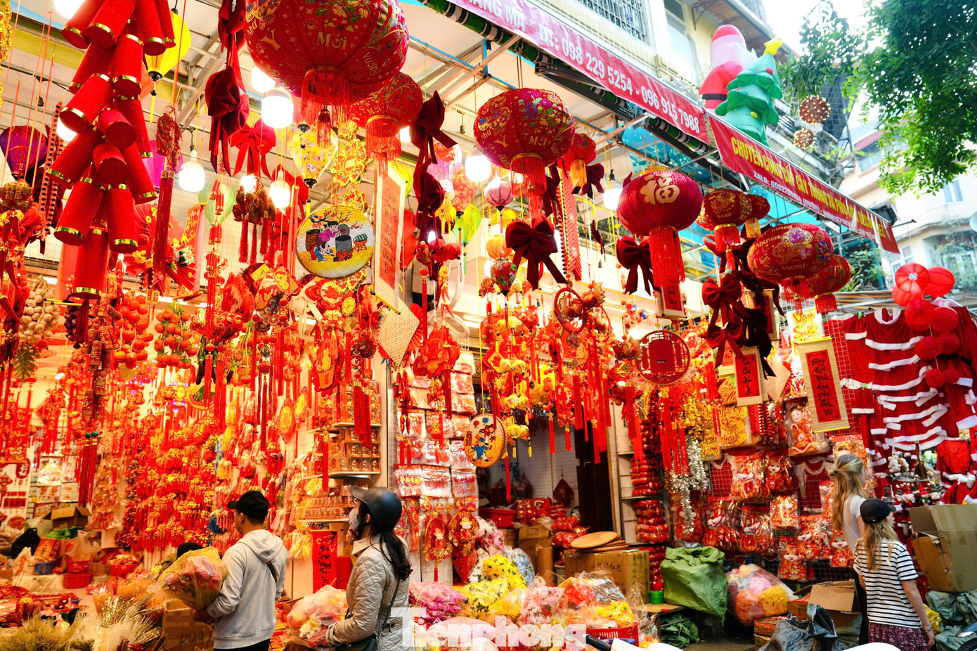 Các cửa hàng bày bán đa dạng đồ trang trí Tết như cành đào, pháo dây, bao lì xì, đèn lồng, câu đối... Các cửa hàng bày bán đa dạng đồ trang trí Tết như cành đào, pháo dây, bao lì xì, đèn lồng, câu đối...