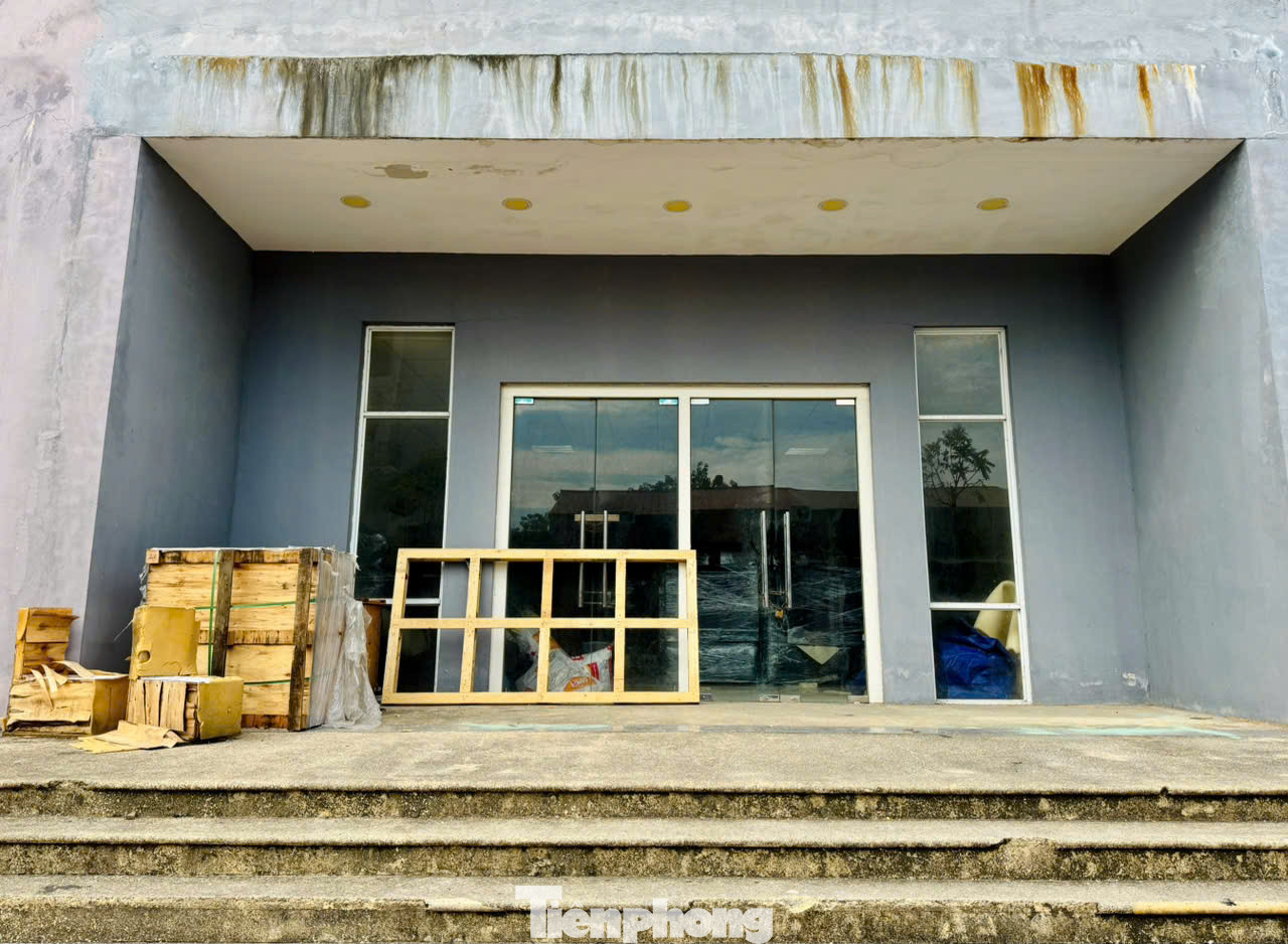 Lối vào sảnh tòa nhà xuống cấp, nhếch nhác, cỏ dại mọc, nhiều điểm tường bong tróc, cửa kính xập xệ, nhiều chỗ còn bị vỡ.