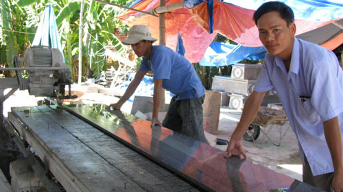 Nguyễn Thành Quỳnh (phải) làm việc cùng công nhân tại cơ sở đá granite của mình. Ảnh: Lê Hải