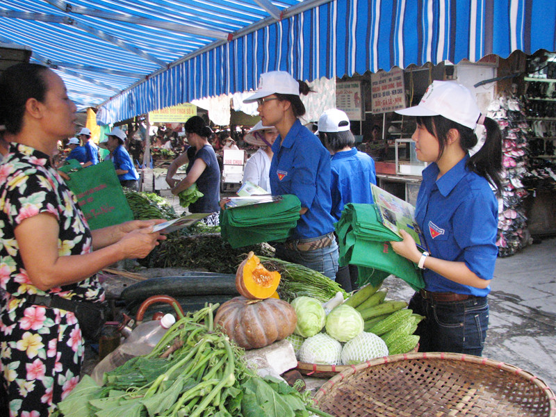 Thanh niên tình nguyện vào chợ phát túi tự hoại để bảo vệ môi trường. Ảnh: Nguyễn Hà
