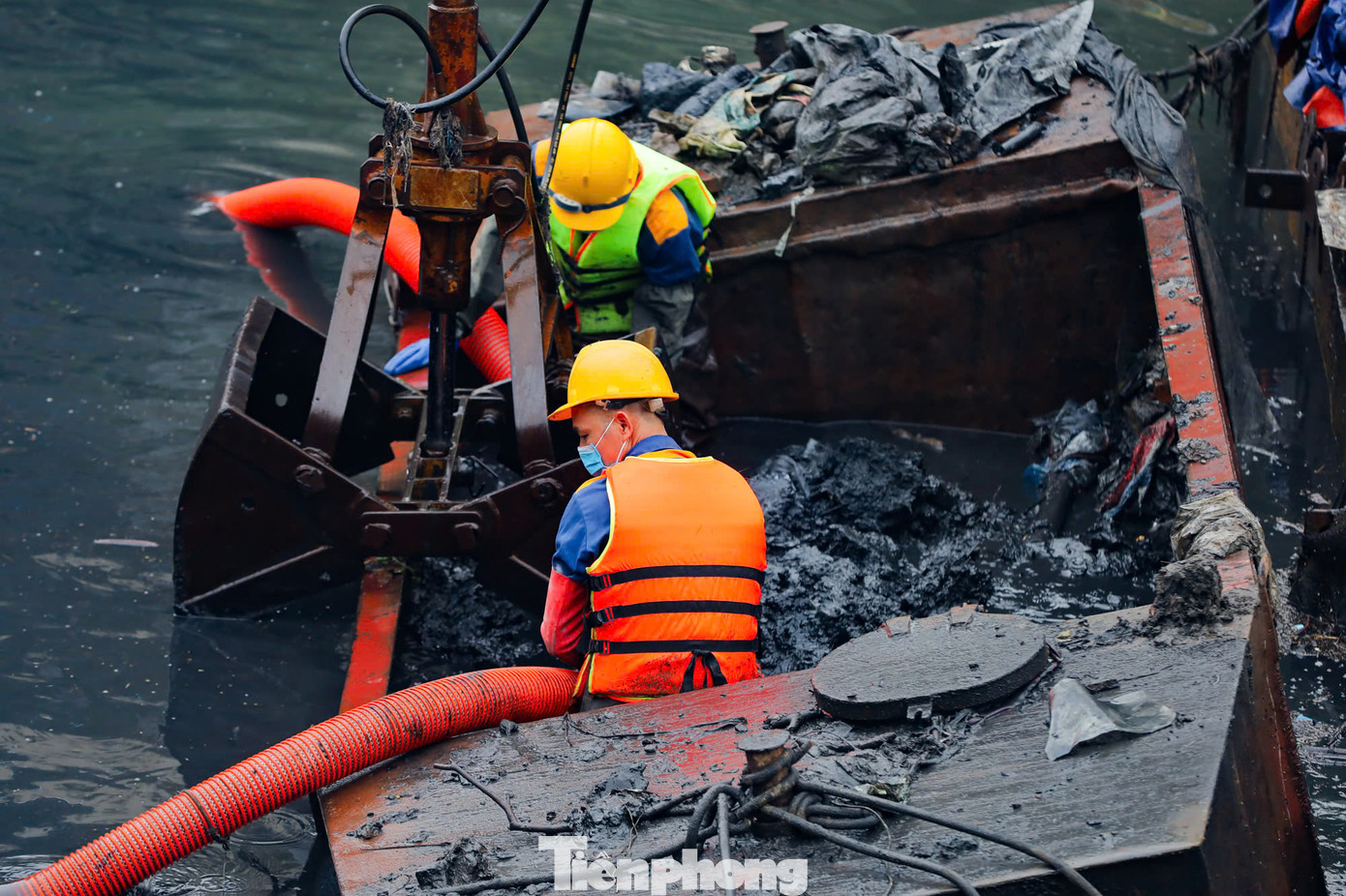 Những mảng bùn thải dày, đặc quánh, đen kịt, bốc mùi hôi thối liên tục được các công nhân cùng thiết bị chuyên dụng xe cẩu nạo vét lên từ đáy sông Tô Lịch.