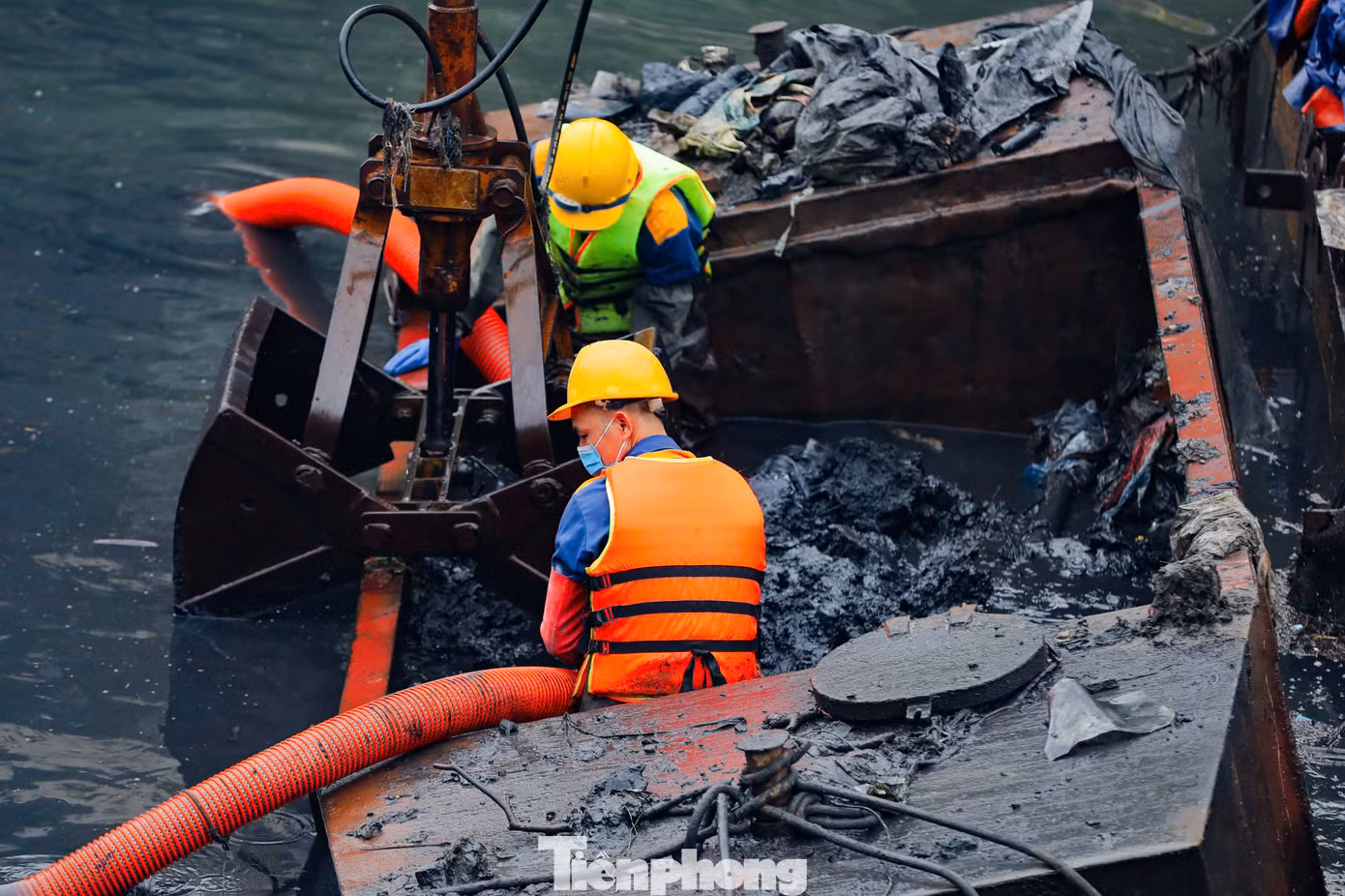 Những mảng bùn thải dày, đặc quánh, đen kịt, bốc mùi hôi thối liên tục được các công nhân cùng thiết bị chuyên dụng xe cẩu nạo vét lên từ đáy sông Tô Lịch.