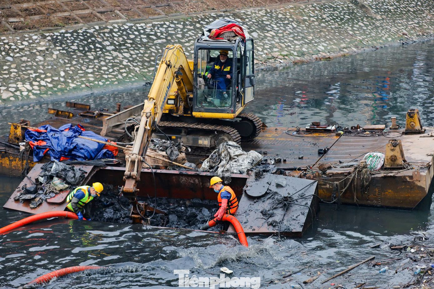 Những mảng bùn thải dày, đặc quánh, đen kịt, bốc mùi hôi thối liên tục được các công nhân cùng thiết bị chuyên dụng xe cẩu nạo vét lên từ đáy sông Tô Lịch.