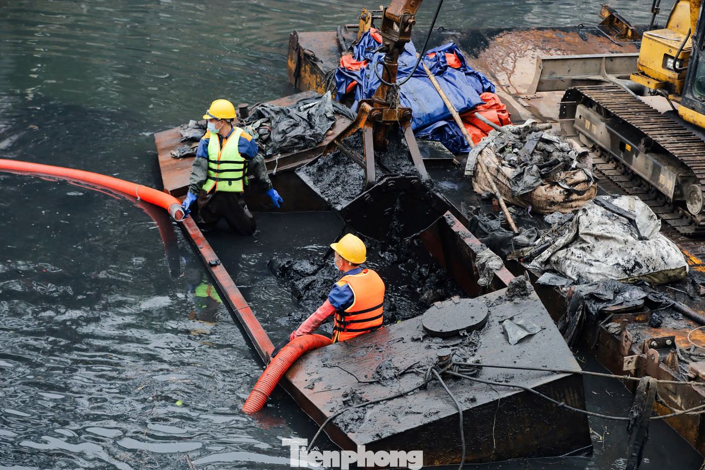 Những mảng bùn thải dày, đặc quánh, đen kịt, bốc mùi hôi thối liên tục được các công nhân cùng thiết bị chuyên dụng xe cẩu nạo vét lên từ đáy sông Tô Lịch.