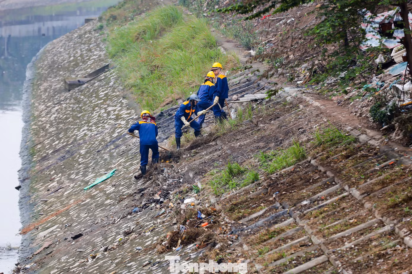 Phía trên bờ, công nhân điều chỉnh hệ thống đường ống dẫn bùn thải từ dưới lòng sông lên xe bồn.
