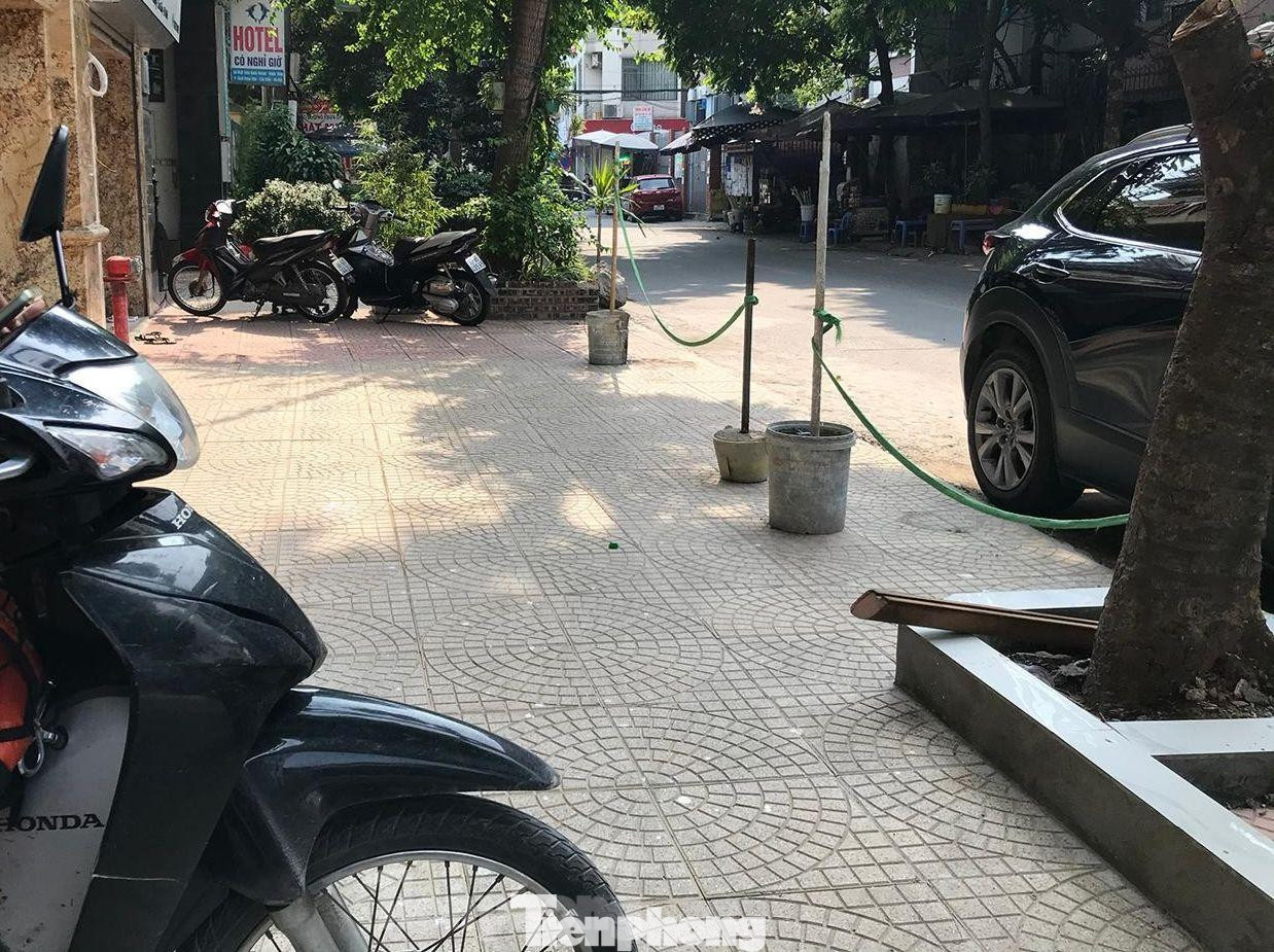 Một đoạn vỉa hè trên phố Trần Quốc Vượng (Cầu Giấy, Hà Nội) được quây kín bằng thùng sơn cắm cọc tre và căng dây để ngăn cản ô tô dừng đỗ. Ảnh: Trường Phong