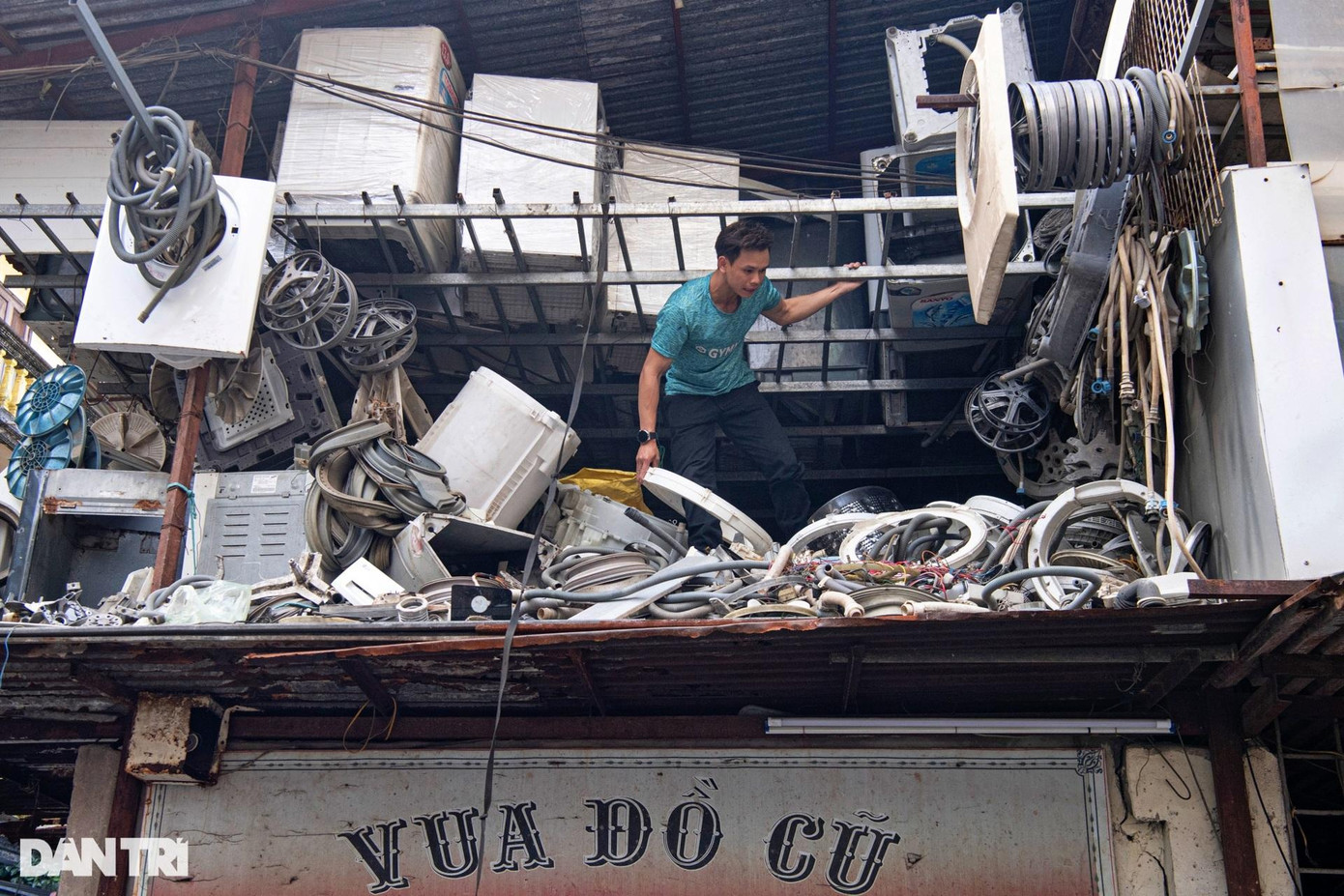Lò Văn Chung, 25 tuổi, quê Sơn La, cách đây 4 năm xuống Hà Nội vừa học nghề vừa làm việc tại "Vua đồ cũ". Chung cho biết: "Lần đầu tiên nhìn thấy căn nhà, tôi từng nghĩ sao chỗ mình làm việc lại bừa bộn như vậy, cũng hơi nguy hiểm. Nhưng về sau, tôi thấy mọi thiết bị đều được cố định chắc chắn nên không ảnh hưởng". Cậu thường bắt đầu công việc lúc 8h; nhận và sửa chữa, tháo lắp các thiết bị, linh kiện điện tử. Do công việc đặc thù, nên cửa hàng không dám vứt bừa các linh kiện, sợ có lúc khách hàng sẽ cần đến. Đây cũng là lý do khiến căn nhà luôn trong tình trạng chất đống đồ đạc. "Mỗi lần đưa đồ từ trên mái nhà xuống, một người phía trên sẽ cố định thiết bị bằng dây rồi từ từ thả xuống dưới trong khi một người khác đứng đợi sẵn để đón lấy", Chung cho hay. Lò Văn Chung, 25 tuổi, quê Sơn La, cách đây 4 năm xuống Hà Nội vừa học nghề vừa làm việc tại "Vua đồ cũ". Chung cho biết: "Lần đầu tiên nhìn thấy căn nhà, tôi từng nghĩ sao chỗ mình làm việc lại bừa bộn như vậy, cũng hơi nguy hiểm. Nhưng về sau, tôi thấy mọi thiết bị đều được cố định chắc chắn nên không ảnh hưởng". Cậu thường bắt đầu công việc lúc 8h; nhận và sửa chữa, tháo lắp các thiết bị, linh kiện điện tử. Do công việc đặc thù, nên cửa hàng không dám vứt bừa các linh kiện, sợ có lúc khách hàng sẽ cần đến. Đây cũng là lý do khiến căn nhà luôn trong tình trạng chất đống đồ đạc. "Mỗi lần đưa đồ từ trên mái nhà xuống, một người phía trên sẽ cố định thiết bị bằng dây rồi từ từ thả xuống dưới trong khi một người khác đứng đợi sẵn để đón lấy", Chung cho hay.