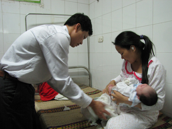 Vợ chồng anh Chiều chuẩn bị cho cháu Trường trước lúc xuất viện. Ảnh: Lãng Phong