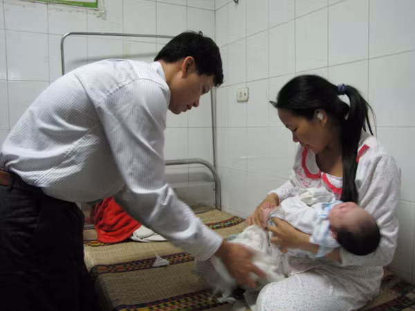 Vợ chồng anh Chiều chuẩn bị cho cháu Trường trước lúc xuất viện. Ảnh: Lãng Phong