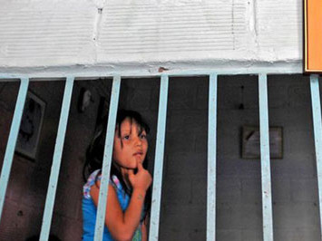 Một bé gái đứng sau khung cửa ở Medellin. independent