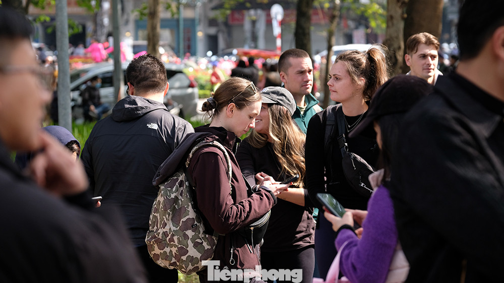 Số lượng khách quá đông khiến những nhóm khách du lịch người nước ngoài phải đứng chờ để được vào tham quan Đền Ngọc Sơn sau khi đã cầm trên tay tấm vé.