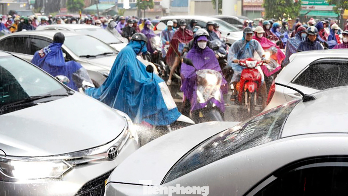 Xe máy len lỏi giữa những hàng ô tô theo kiểu &quot;điền vào chỗ trống&quot; khi cảnh ùn tắc diễn ra dưới trời mưa to.