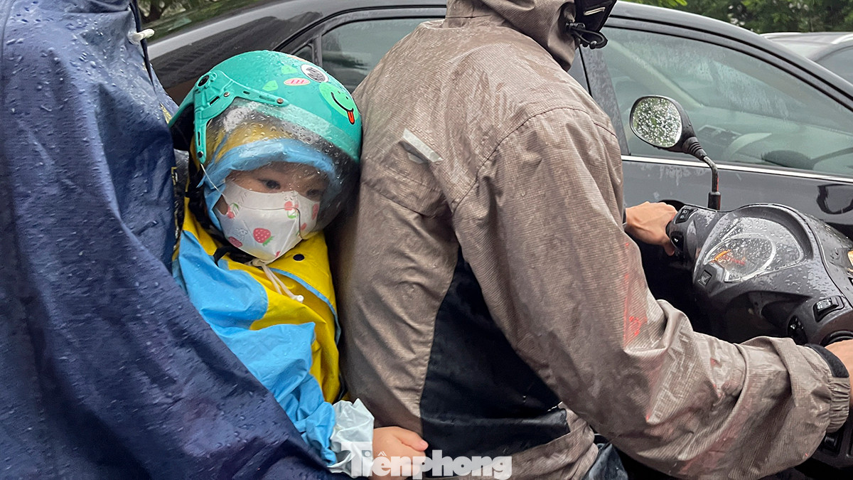 Một em nhỏ được bố mẹ đưa đến trường mẫu giáo đúng vào thời điểm mưa to kèm tắc đường trên đoạn đường Hoàng Minh Giám.