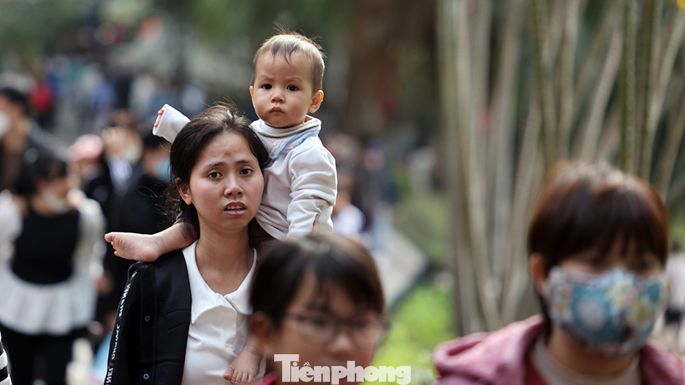 Một em bé được mẹ cho ngồi trên vai để tránh sự chen lấn khi lượng khách đổ về vườn thú rất đông vào ngày nghỉ lễ này.