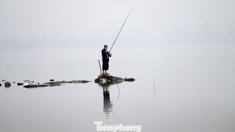 Một người đàn ông đứng câu cá trong tiết trời mù mịt ở một góc Hồ Tây vào chiều 3/2.