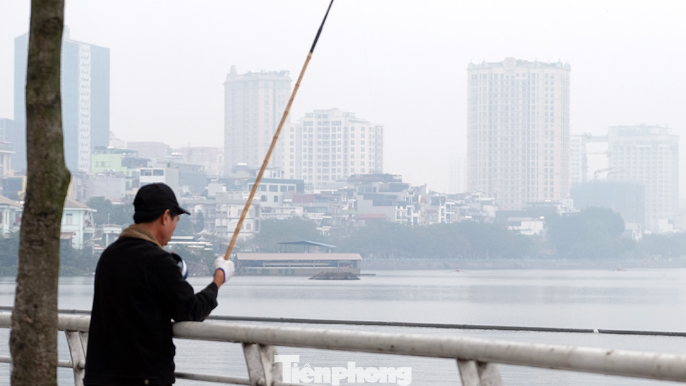 Một người đàn ông quăng câu bên Hồ Tây thời điểm gần trưa.