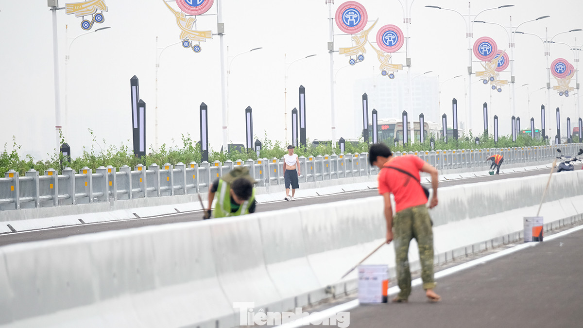 Công nhân đang quét sơn dải phân cách và vệ sinh bề mặt cầu. Những công việc được coi là cuối cùng trước khi dự án được đưa vào sử dụng.