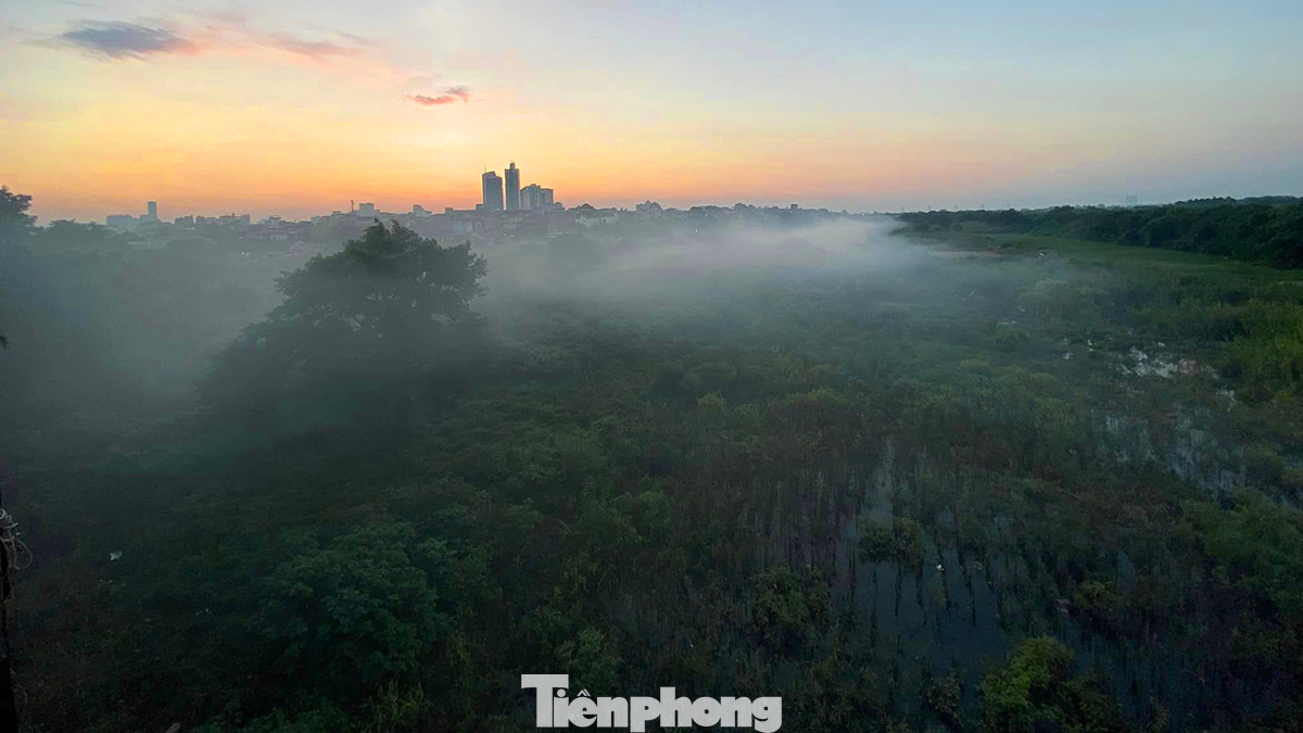 Vào thời điểm mặt trời dần khuất dần sau dãy núi Ba Vì phía xa, những làn sương khói mờ ảo xuất hiện nhiều phía dưới bãi giữa của khu vực chân cầu Long Biên.