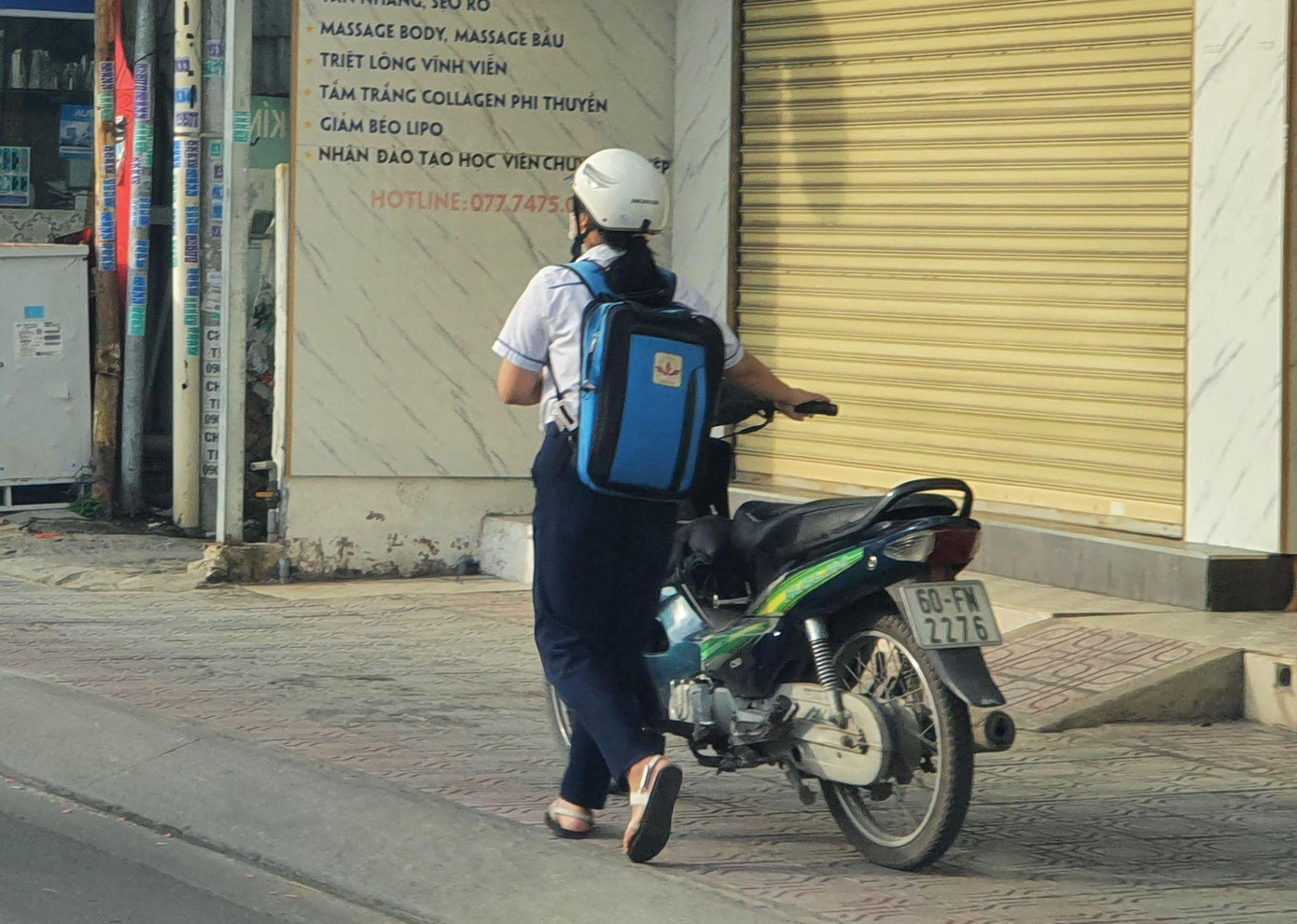 Một học sinh phải dắt xe đến trường vì hết xăng.