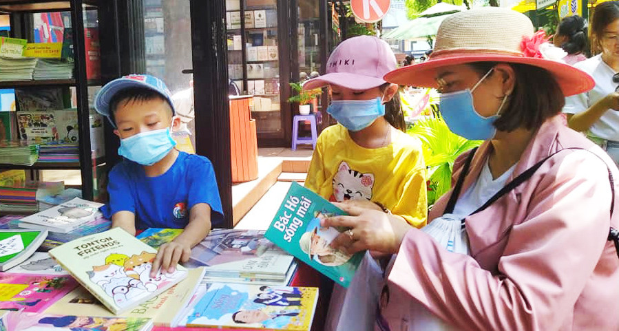 Một em bé đang thuyết phục mẹ cho mua cuốn sách yêu thích