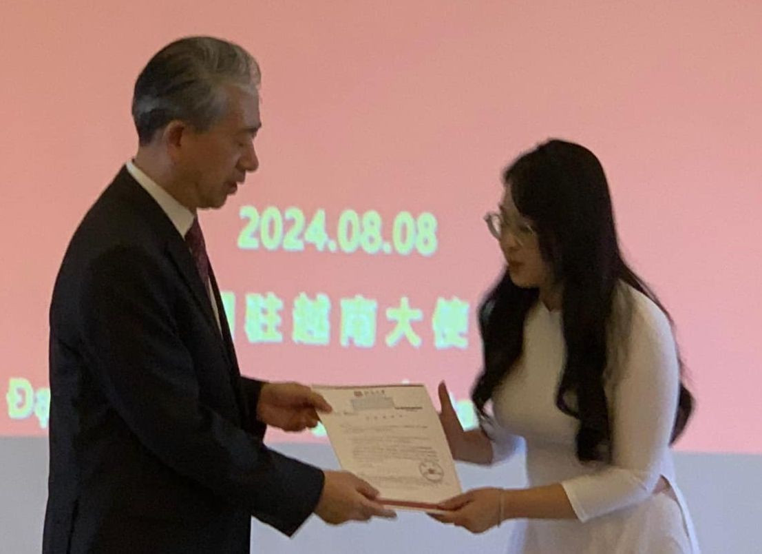 Đại sứ Trung Quốc Hùng Ba trao giấy nhập học cho sinh viên Việt Nam. Ảnh: Thái An